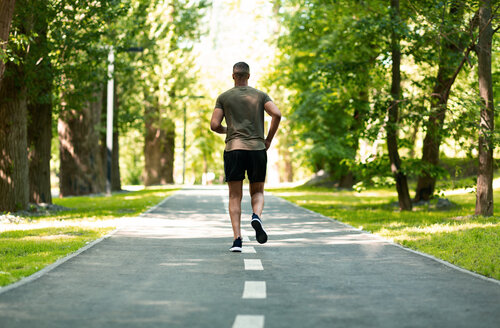 back-view-of-jogger-running-at-green-park-on-summe-RESWZDK